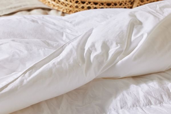 Κοντινό πλάνο του Boll & Branch Down Alternative Duvet Insert διπλωμένο σε ένα κρεβάτι 
