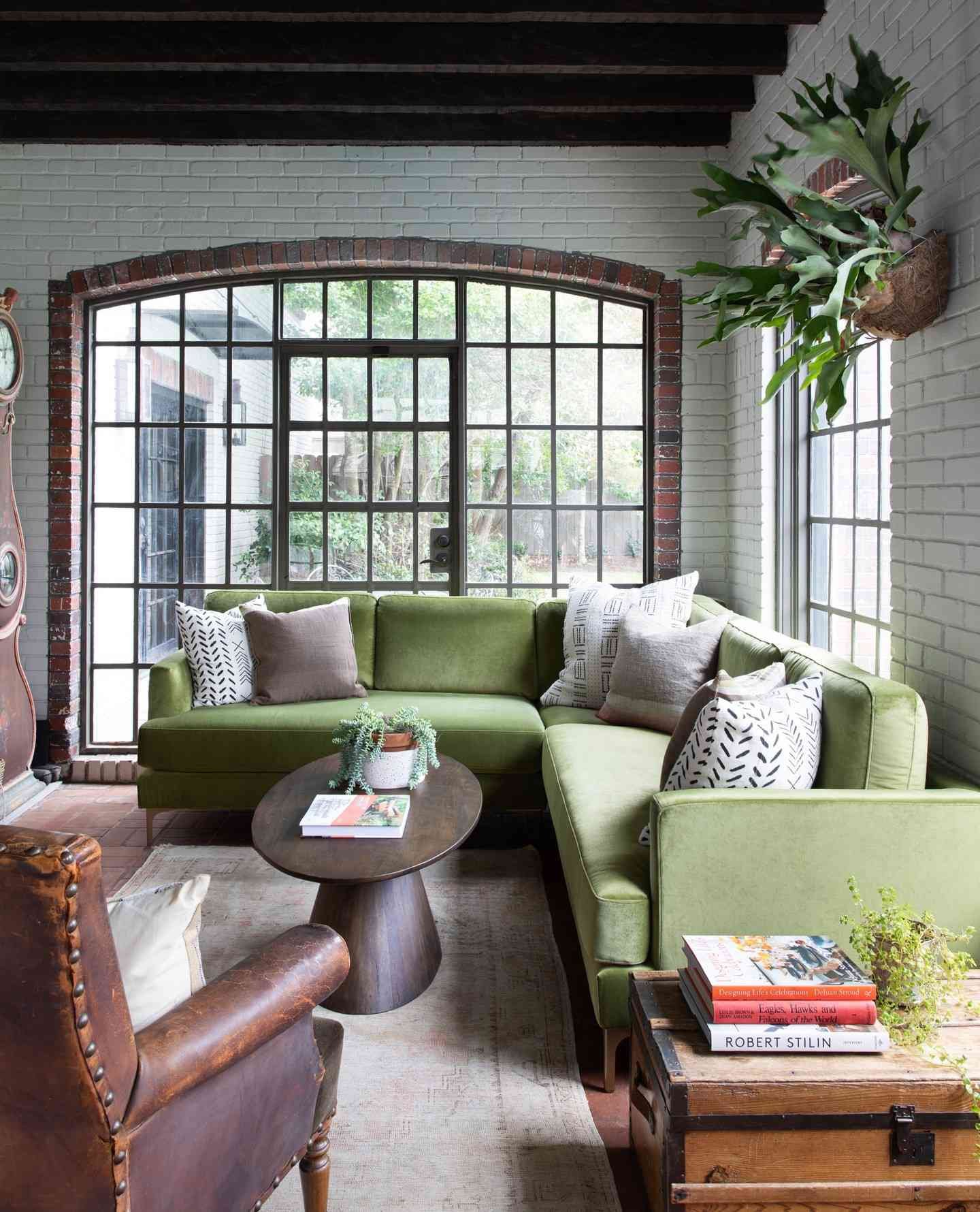 sage green sectional in white living room with wall plants