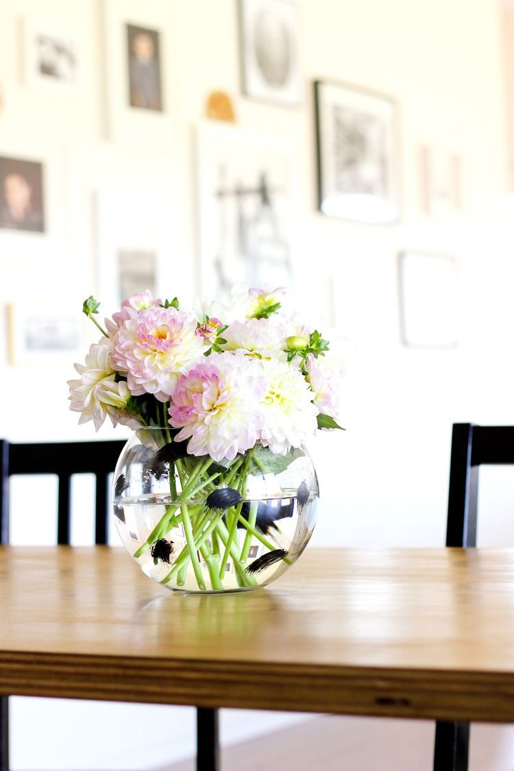 A table with a glass vase painted in black sitting on it