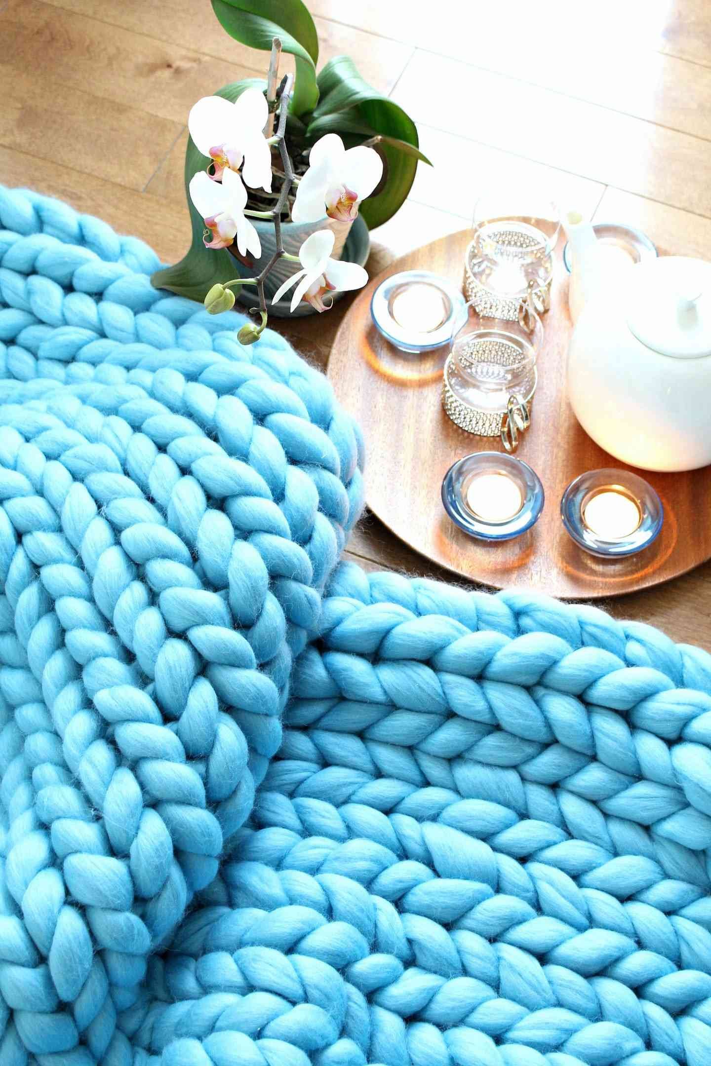 A blue arm knit blanket next to candles