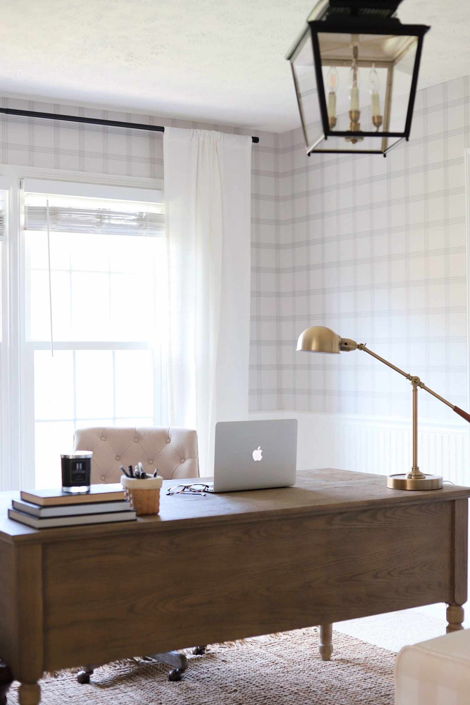 Lantern-style pendant light above a desk in a home office with a grid wallpaper