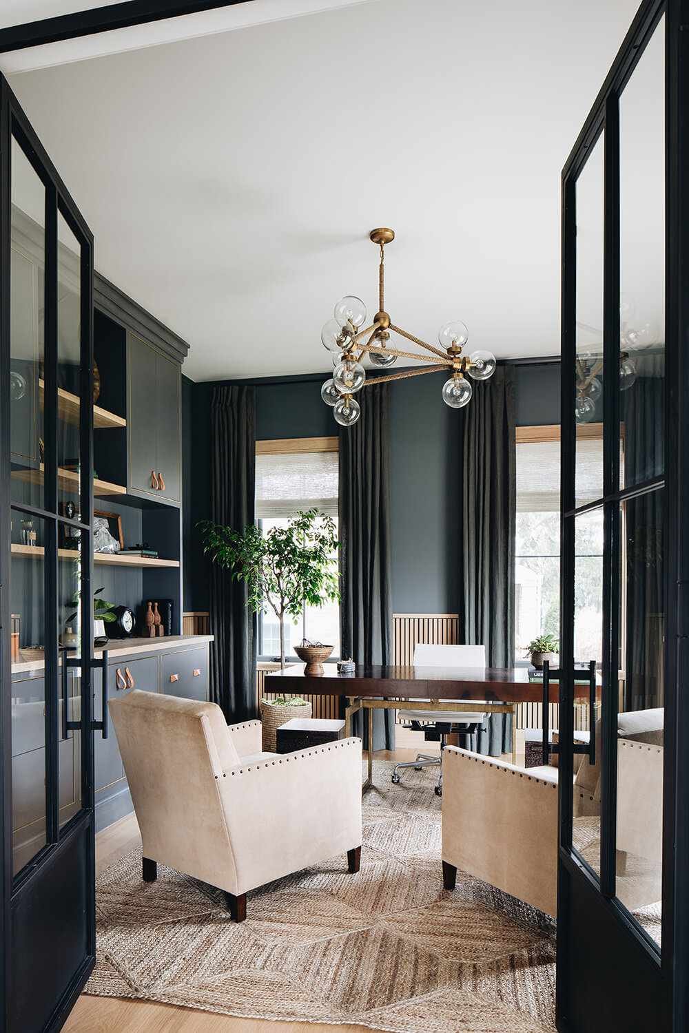 Brass sputnik chandelier in a home office with black walls and modern furniture