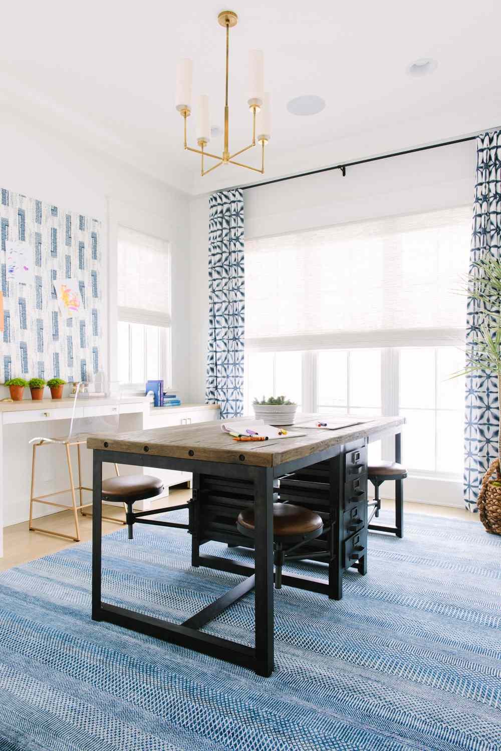 Modern brass candelabra in a home office with a wood and metal table in the center