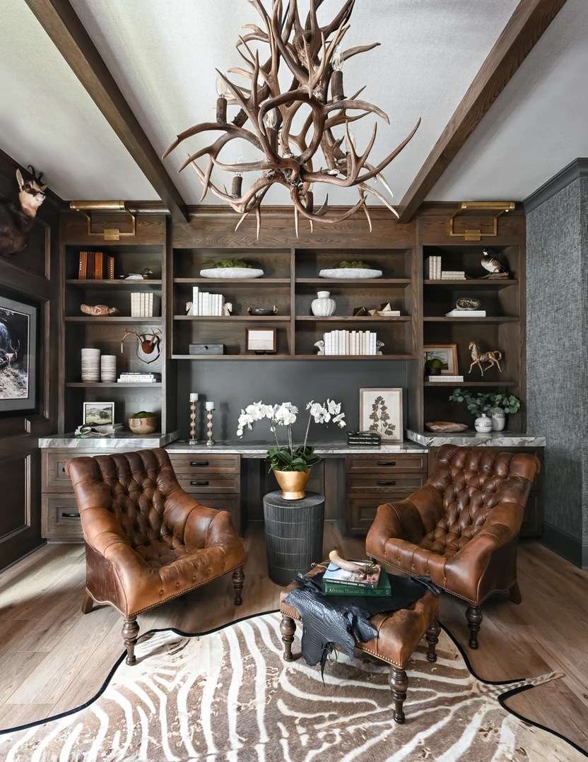 Antler chandelier in a modern rustic home office with leather chairs and wood built-ins