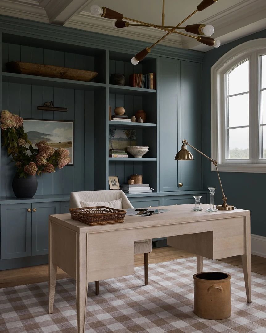 Brass exposed bulb chandelier in a home office with a wood desk and slate blue built-ins