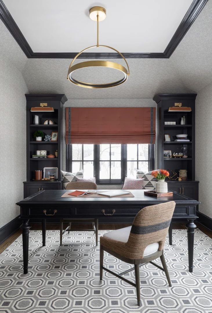 Modern brass ceiling light fixture in an office with a black desk and built-ins