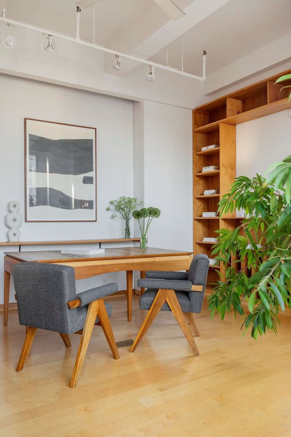 White track lighting above a wood desk in a home office with wood built-ins
