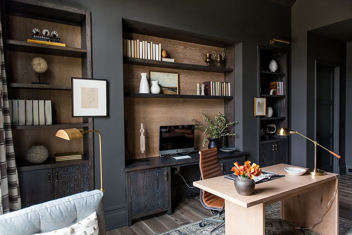 Brass task light on a wooden desk in a dark and moody home office