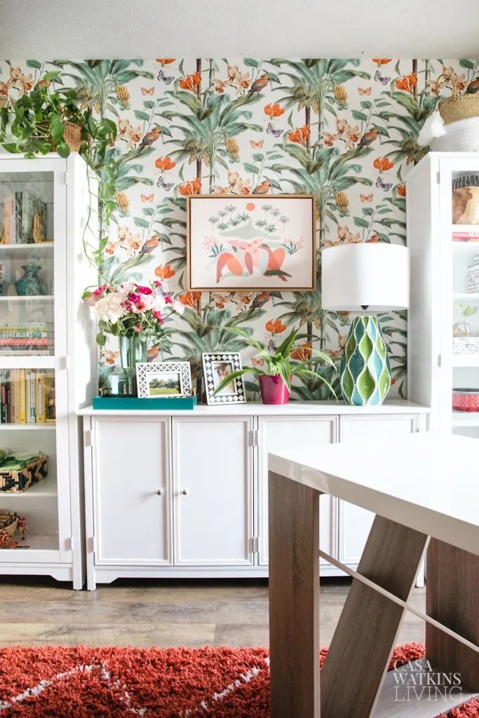Colorful ceramic table lamp on a white console in a home office with a fun tropical wallpaper
