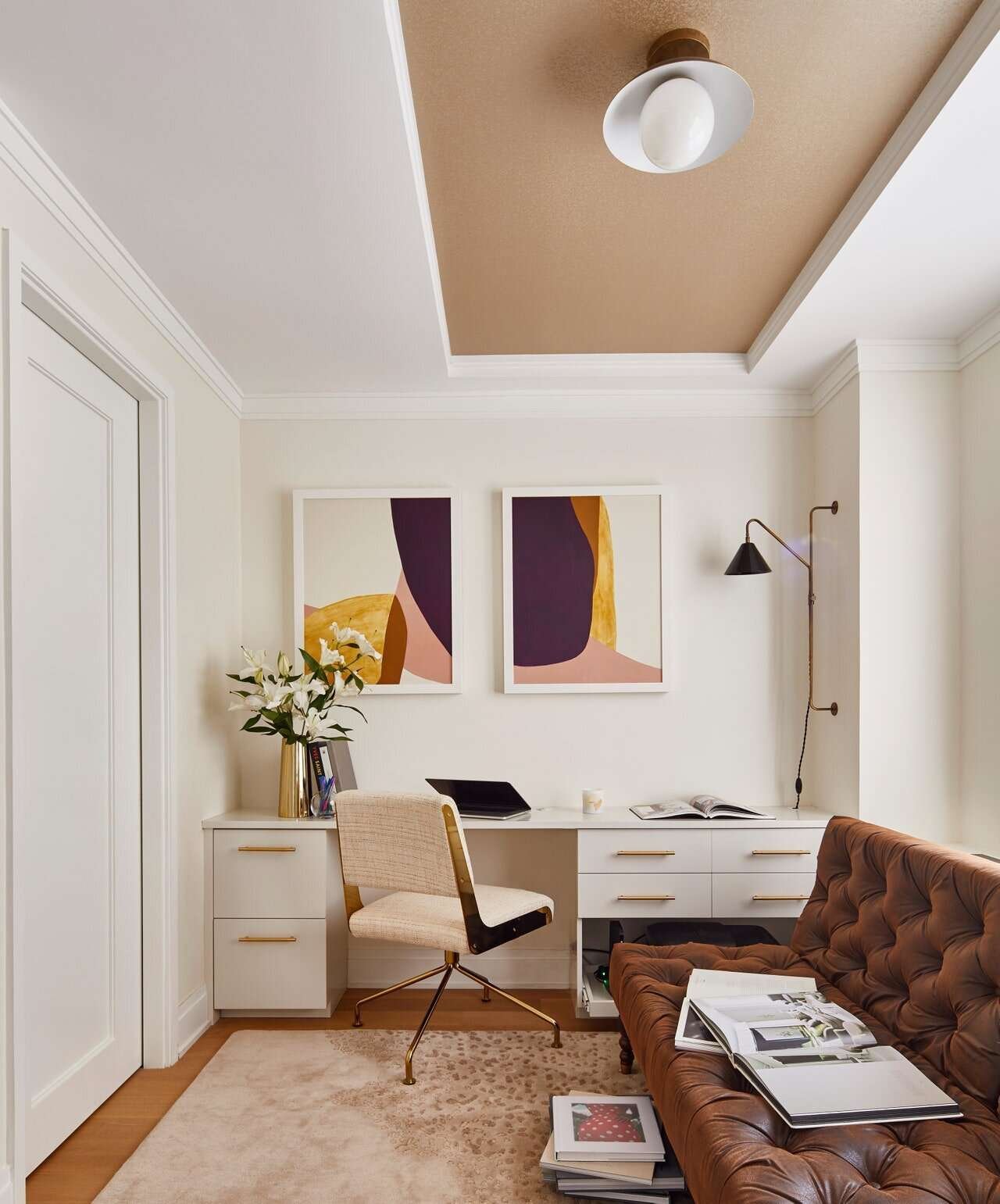 Black wall sconce above a white desk in a modern home office