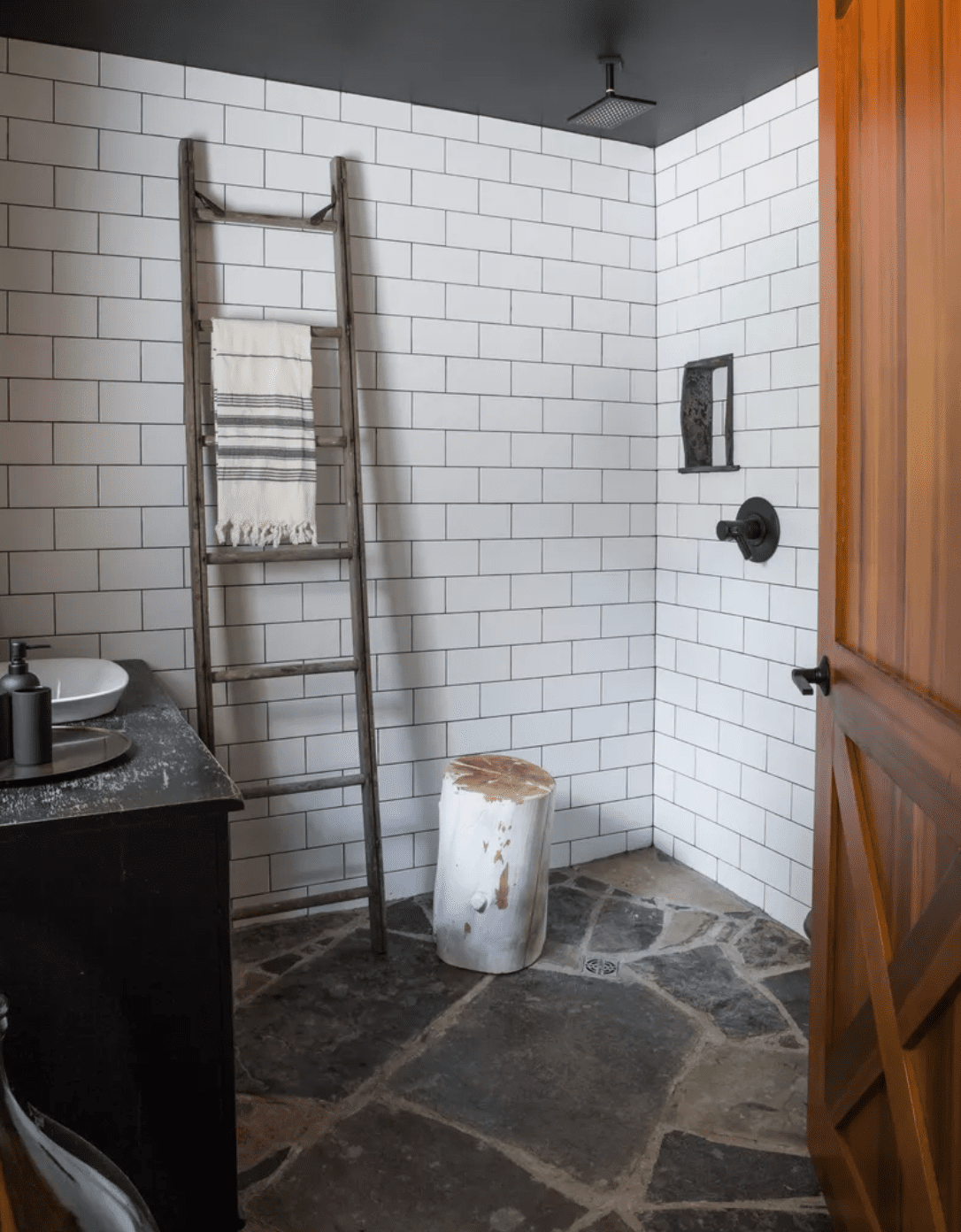 A bathroom shower with tiled walls and stone floors