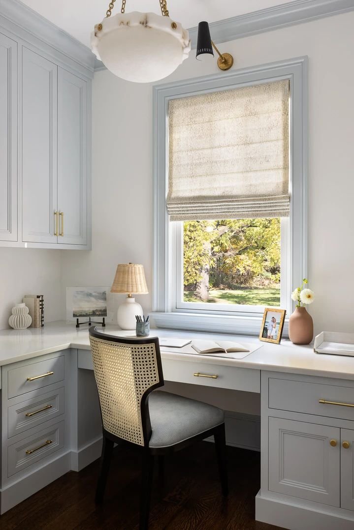 White pendant light in an office with light blue built-ins and trim