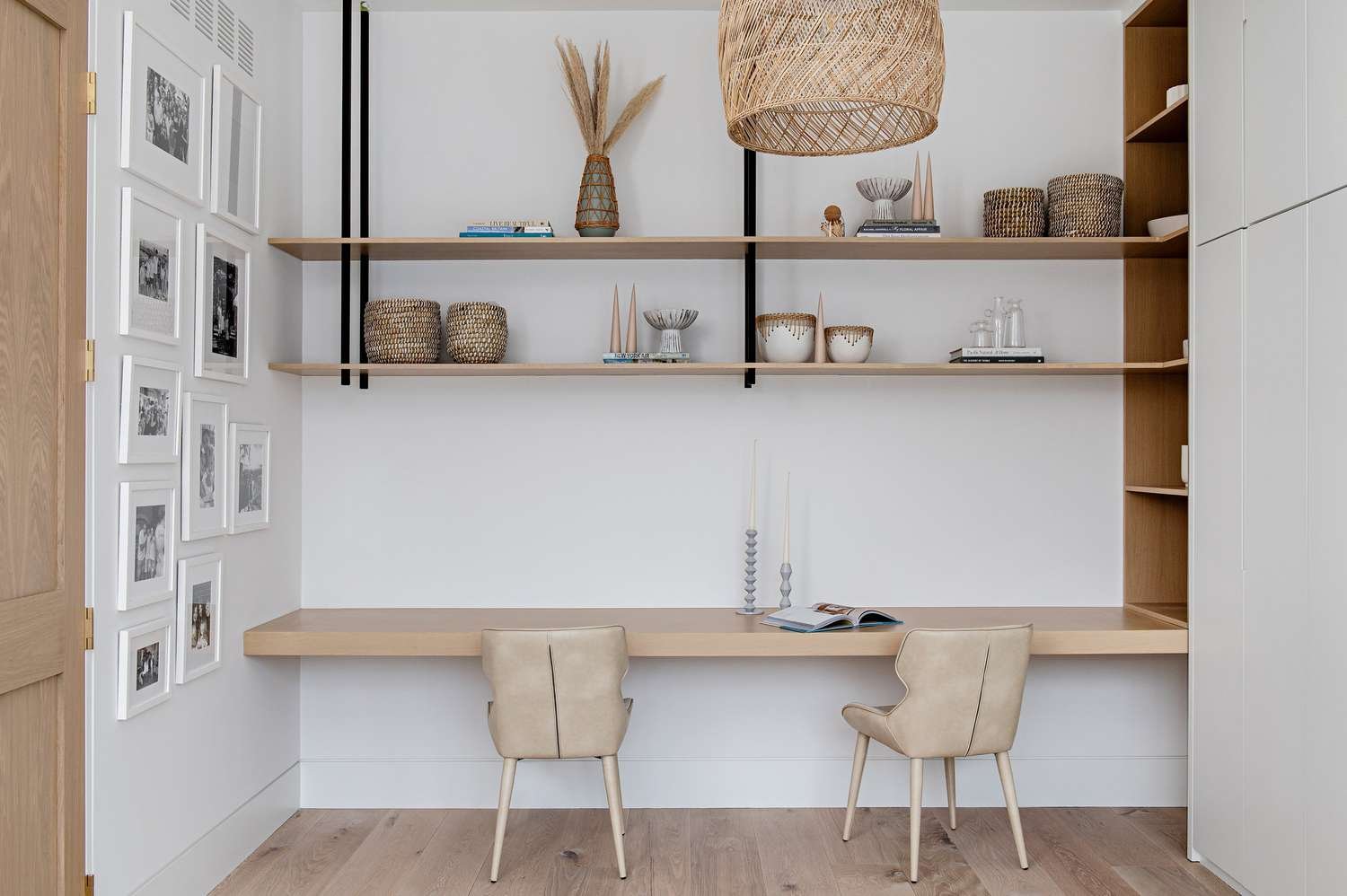 Rattan pendant light hanging in a home office with a wood built-in desk and shelves above it